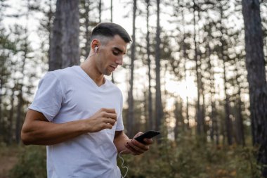 Sabah koşarken cep telefonu kullanan bir sporcunun portresi kulaklıkla müzik dinleyen atletik bir adam cep telefonu uygulaması kullanıyor