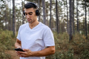 Sabah koşarken cep telefonu kullanan bir sporcunun portresi kulaklıkla müzik dinleyen atletik bir adam cep telefonu uygulaması kullanıyor