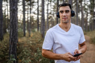 Sabah koşarken cep telefonu kullanan bir sporcunun portresi kulaklıkla müzik dinleyen atletik bir adam cep telefonu uygulaması kullanıyor