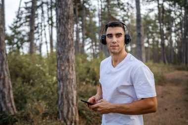 Sabah koşarken cep telefonu kullanan bir sporcunun portresi kulaklıkla müzik dinleyen atletik bir adam cep telefonu uygulaması kullanıyor
