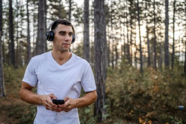 Sabah koşarken cep telefonu kullanan bir sporcunun portresi kulaklıkla müzik dinleyen atletik bir adam cep telefonu uygulaması kullanıyor