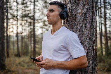 Sabah koşarken cep telefonu kullanan bir sporcunun portresi kulaklıkla müzik dinleyen atletik bir adam cep telefonu uygulaması kullanıyor