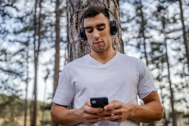 Sabah koşarken cep telefonu kullanan bir sporcunun portresi kulaklıkla müzik dinleyen atletik bir adam cep telefonu uygulaması kullanıyor