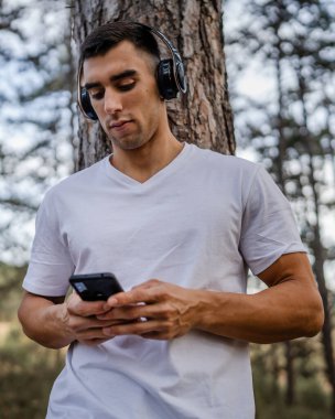 Sabah koşarken cep telefonu kullanan bir sporcunun portresi kulaklıkla müzik dinleyen atletik bir adam cep telefonu uygulaması kullanıyor