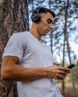 Sabah koşarken cep telefonu kullanan bir sporcunun portresi kulaklıkla müzik dinleyen atletik bir adam cep telefonu uygulaması kullanıyor