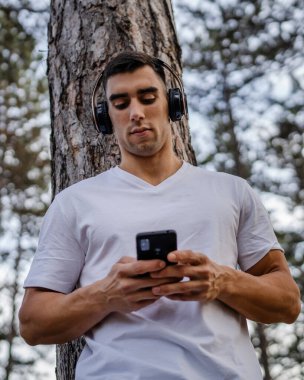 Sabah koşarken cep telefonu kullanan bir sporcunun portresi kulaklıkla müzik dinleyen atletik bir adam cep telefonu uygulaması kullanıyor