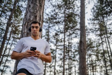 Sabah koşarken cep telefonu kullanan bir sporcunun portresi kulaklıkla müzik dinleyen atletik bir adam cep telefonu uygulaması kullanıyor