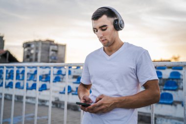 Sabah koşarken cep telefonu kullanan bir sporcunun portresi kulaklıkla müzik dinleyen atletik bir adam cep telefonu uygulaması kullanıyor