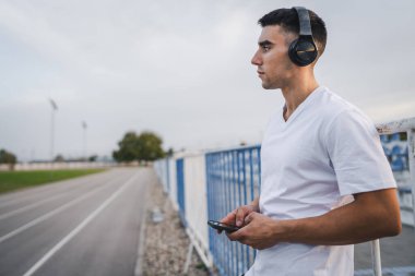 Sabah koşarken cep telefonu kullanan bir sporcunun portresi kulaklıkla müzik dinleyen atletik bir adam cep telefonu uygulaması kullanıyor