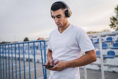 Sabah koşarken cep telefonu kullanan bir sporcunun portresi kulaklıkla müzik dinleyen atletik bir adam cep telefonu uygulaması kullanıyor