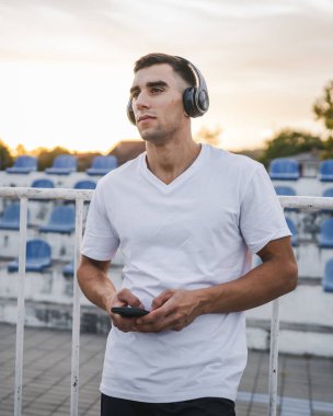 Sabah koşarken cep telefonu kullanan bir sporcunun portresi kulaklıkla müzik dinleyen atletik bir adam cep telefonu uygulaması kullanıyor