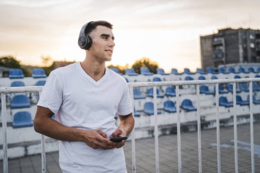 Sabah koşarken cep telefonu kullanan bir sporcunun portresi kulaklıkla müzik dinleyen atletik bir adam cep telefonu uygulaması kullanıyor