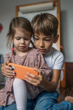 Ağabey kız kardeşle akıllı telefon kullan. Çocuklar evde cep telefonu kullan. Video izle, ara ya da oyun oyna.