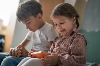 Ağabey kız kardeşle akıllı telefon kullan. Çocuklar evde cep telefonu kullan. Video izle, ara ya da oyun oyna.