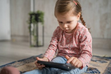 Bir beyaz çocuk cep telefonunu evde tutuyor video oyunları oynuyor ve büyüyen teknoloji bağımlılığı kavramı online tarama veya video izlemek için uygulama kullanıyor