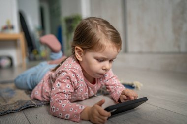 Bir beyaz çocuk cep telefonunu evde tutuyor video oyunları oynuyor ve büyüyen teknoloji bağımlılığı kavramı online tarama veya video izlemek için uygulama kullanıyor