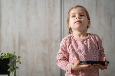 Bir beyaz çocuk cep telefonunu evde tutuyor video oyunları oynuyor ve büyüyen teknoloji bağımlılığı kavramı online tarama veya video izlemek için uygulama kullanıyor