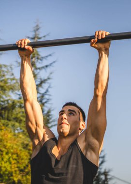 Açık spor salonunda antrenman yapan genç bir beyaz erkek sporcu şehirde yaz günü sağlıklı yaşam tarzı ve dinlenme eğitimi alıyor.