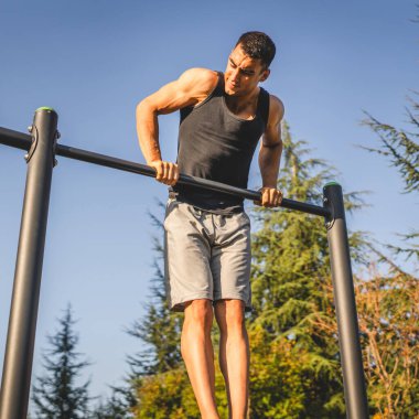 Açık spor salonunda antrenman yapan genç bir beyaz erkek sporcu şehirde yaz günü sağlıklı yaşam tarzı ve dinlenme eğitimi alıyor.