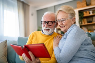 Üst düzey karı koca aile fotoğraflarına bakıyor. Kafkasyalı yaşlı erkek ve kadın büyükbaba ve büyükanne mutlu bir gülümseme. Evde eski resimlerle gerçek insanlar uzay kopyaları yapıyor.