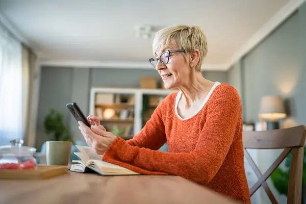 one mature senior caucasian woman use mobile phone smartphone at home