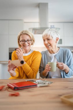 Yetişkin kadın arkadaşlar ya da kız kardeşler aile fotoğraflarına bakıyor. İki beyaz kadın evde oturup gülümserken gerçek insanlar uzayı kopyalıyor.
