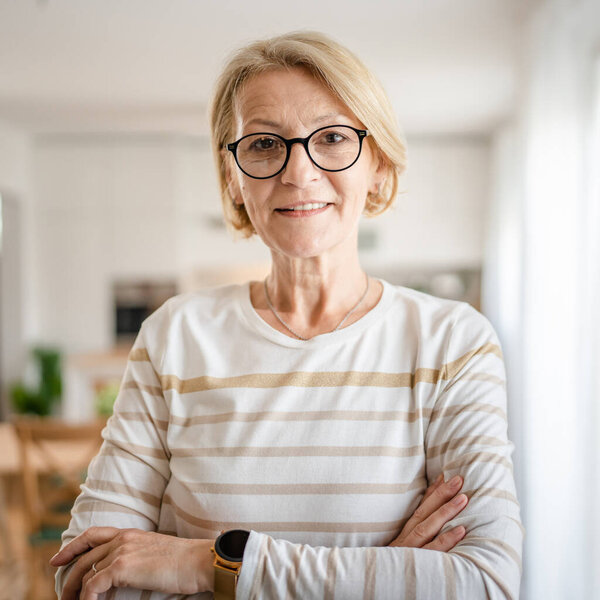 Портрет одной зрелой белокурой белокурой женщины в очках дома счастливая улыбка глядя в камеру уверенно носить свитер в яркой комнате копировать пространство