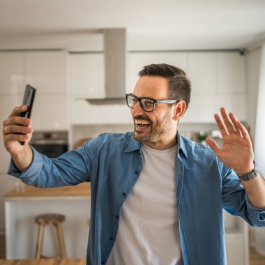 Beyaz erkek mutlu adam görüntülü sohbet görüşmesi yapıyor. Evdeki akıllı cep telefonundan.