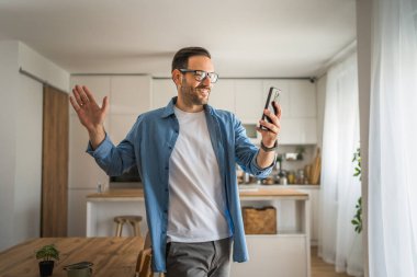 Beyaz erkek mutlu adam görüntülü sohbet görüşmesi yapıyor. Evdeki akıllı cep telefonundan.