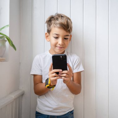 Küçük beyaz bir çocuk cep telefonu tutuyor. Akıllı telefon, fotoğraf çekiyor.