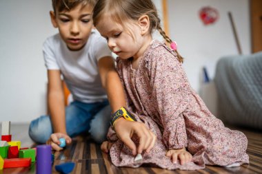 Small caucasian boy and girl siblings brother and sister children play at home sit on the floor at home childhood development growing up concept copy space domestic life
