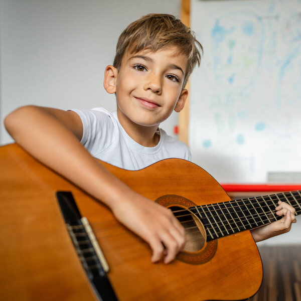 Cute boy learns to play the classical guitar