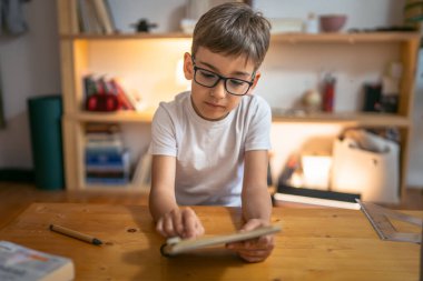 Genç çocuk öğrenci ödevlerini evde yapıyor.