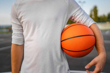 Bilinmeyen bir gencin orta kesiminde, Kafkas kökenli bir genç adam basketbol sahasında duruyor. Akşamları top ile fotokopi çekmeye hazır.