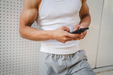 Dışarıdaki genç adamın portresi müzik yapmak ya da video yayını izlemek için kulaklık ve akıllı telefon kullanıyor.