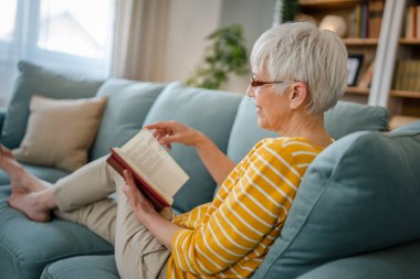 Yetişkin, yaşlı, Kafkasyalı, emekli, modern, kitap okuyan bir kadın gözlük takıyor.