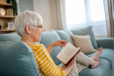 Yetişkin, yaşlı, Kafkasyalı, emekli, modern, kitap okuyan bir kadın gözlük takıyor.