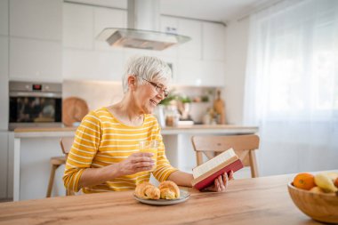 Yetişkin, yaşlı, Kafkasyalı, emekli, modern, kitap okuyan bir kadın gözlük takıyor.