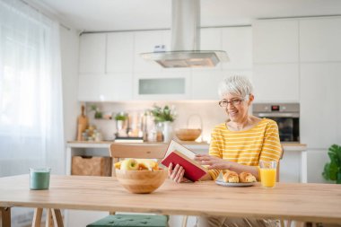 Yetişkin, yaşlı, Kafkasyalı, emekli, modern, kitap okuyan bir kadın gözlük takıyor.