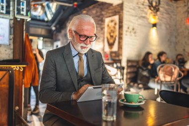 Bir üst düzey Kafkas erkek iş adamı Kafe 'de dijital tablet kullanıyor. Kıyafet fotokopi alanı kullanıyor.