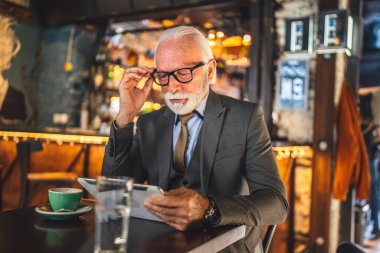 Bir üst düzey Kafkas erkek iş adamı dijital tablet kullanıyor kafe de oturup fotokopi odası takıyor ve kötü haber problemini çözmekten endişe ediyor.