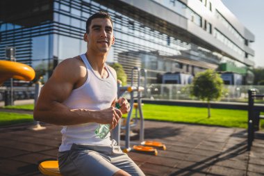 Beyaz tenli bir erkek sporcu plastik su şişesini açık tutuyor ve açık havada güneşli su ve sağlıklı yaşam tarzı konsepti fotokopi çekerken içmeye hazırlanıyor.