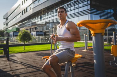 Beyaz tenli bir erkek sporcu plastik su şişesini açık tutuyor ve açık havada güneşli su ve sağlıklı yaşam tarzı konsepti fotokopi çekerken içmeye hazırlanıyor.