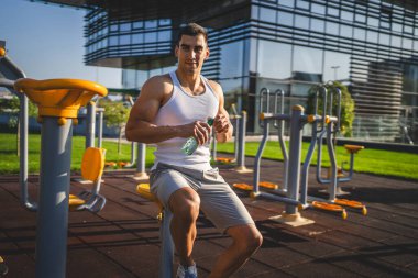 Beyaz tenli bir erkek sporcu plastik su şişesini açık tutuyor ve açık havada güneşli su ve sağlıklı yaşam tarzı konsepti fotokopi çekerken içmeye hazırlanıyor.