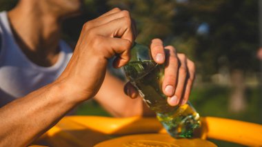 Beyaz tenli bir erkek sporcu plastik su şişesini açık tutuyor ve açık havada güneşli su ve sağlıklı yaşam tarzı konsepti fotokopi çekerken içmeye hazırlanıyor.