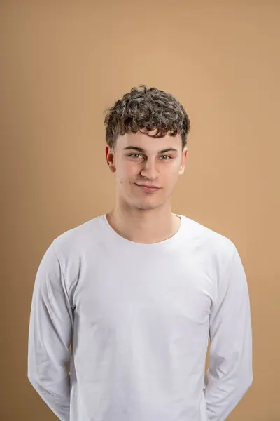 stock image Portrait of one caucasian man 20 years old looking to the camera in front of almond color studio background wearing casual shirt copy space