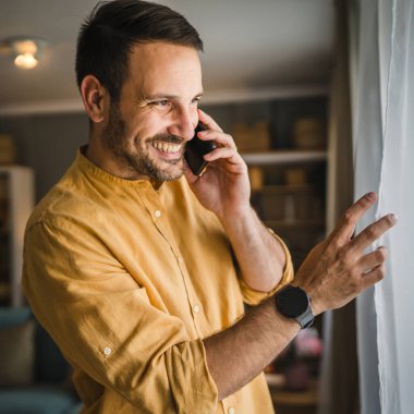 Yetişkin bir beyaz erkek cep telefonuyla arama yapar. Mutlu bir gülümseme, tişört ve gözlük takar. Gerçek bir insanı taklit eder.