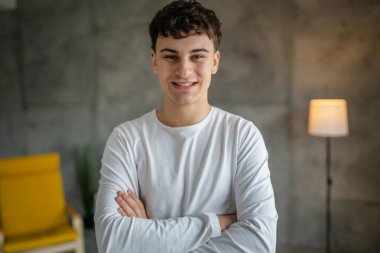 20 yaşındaki beyaz bir adamın portresi. Evinde kameraya bakıp gülümsüyor. Günlük beyaz gömlek giyip fotokopi çekiyor.