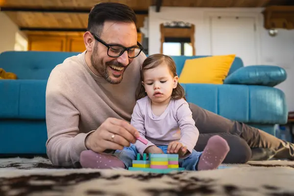 Father and daughter play on the floor at home mature adult caucasian man play with his two years old child toddler girl having fun parenting and bonding family time concept copy space real people