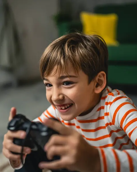 一个男孩坐在家里拿着控制杆玩游戏机 — 图库照片
